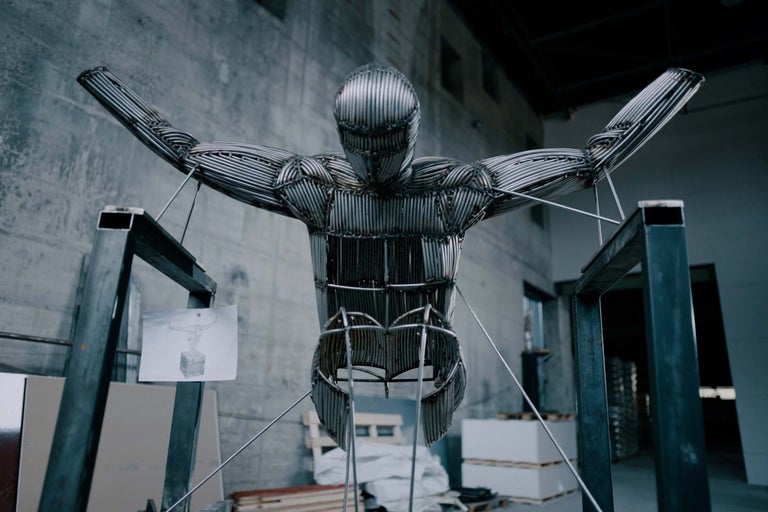 Skulptur eines Mannes aus Metallstäben in einem Lager