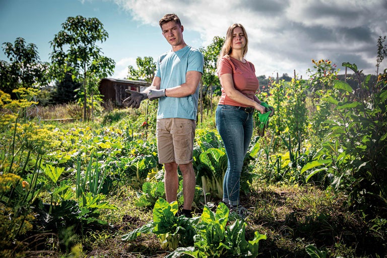 Ein Mann und eine Frau stehen in einem Gemüsegarten.