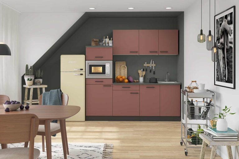 Helle Küche mit Küchenschränken, Kühlschrank, Mikrowelle, Esstisch und Servierwagen.