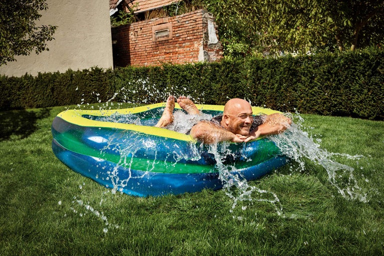 Mann planscht im aufblasbaren Pool im Garten