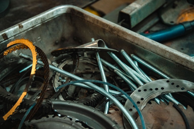 Eine Metallkiste gefüllt mit Schrauben, Muttern, Zahnrädern und Metallstangen