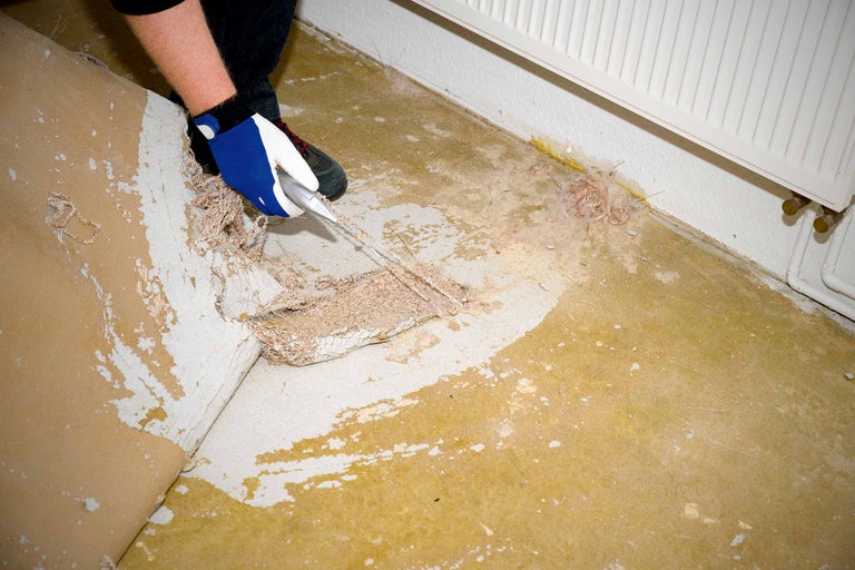 Entfernung von Teppichboden mit einem Schaber in einem Raum mit Heizkörper