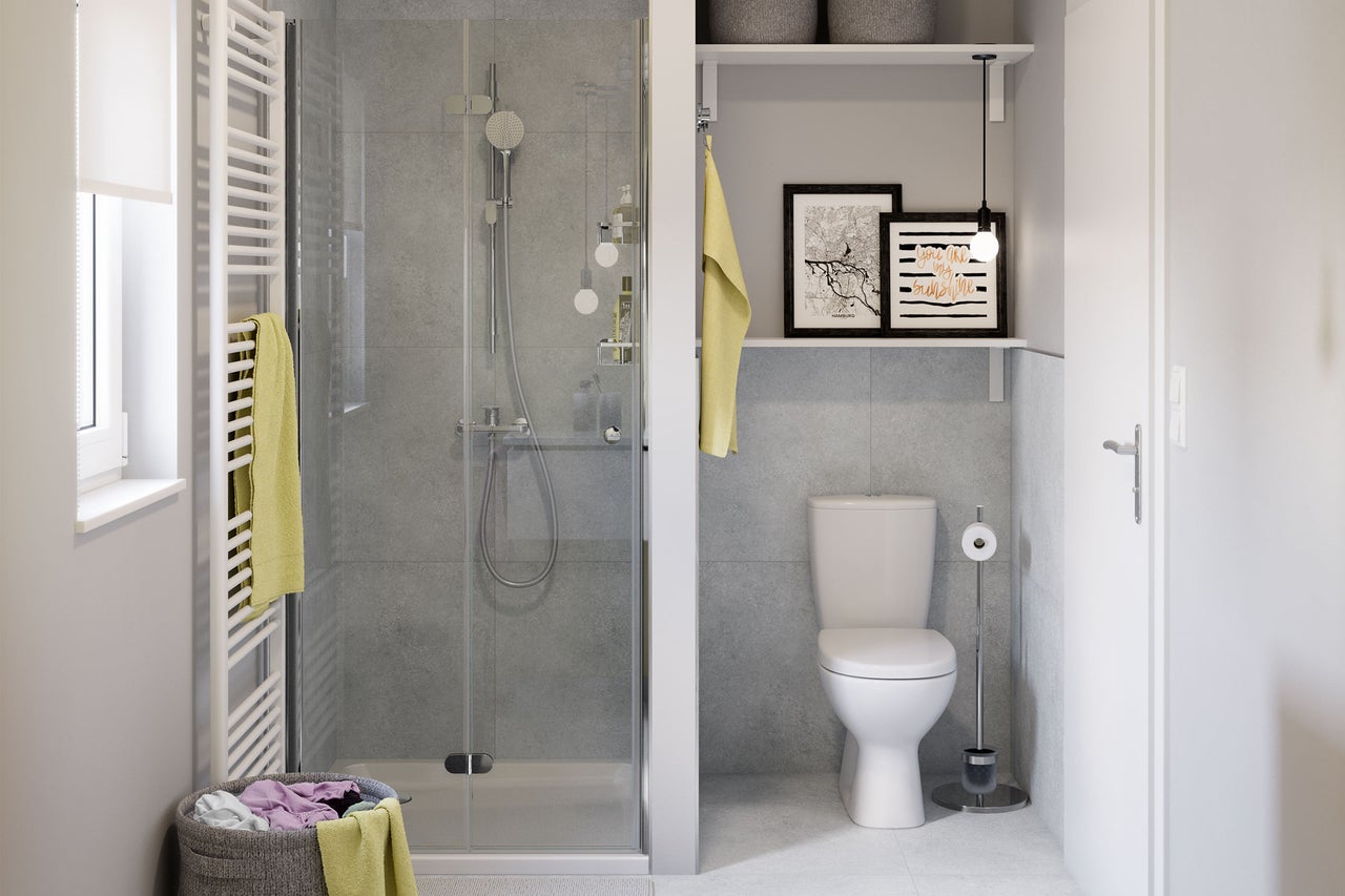 Modernes, helles Badezimmer mit Glasdusche, grau gefliesten Wänden, weißer Toilette und einem Handtuchheizkörper.