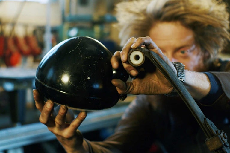 Eine Person hält eine schwarze Lampe und ein Metallteil.