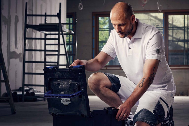 Handwerker mit Werkzeugkoffer in einem Raum mit Baugerüst