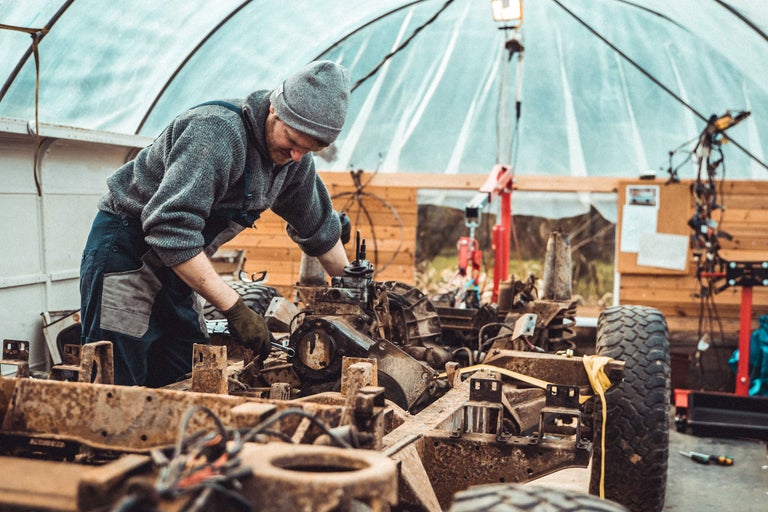 Ein Mechaniker arbeitet an einem Fahrzeugrahmen in einer Werkstatt.