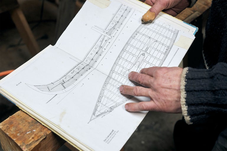 Eine Person betrachtet eine Bootsbauzeichnung in einem Buch.