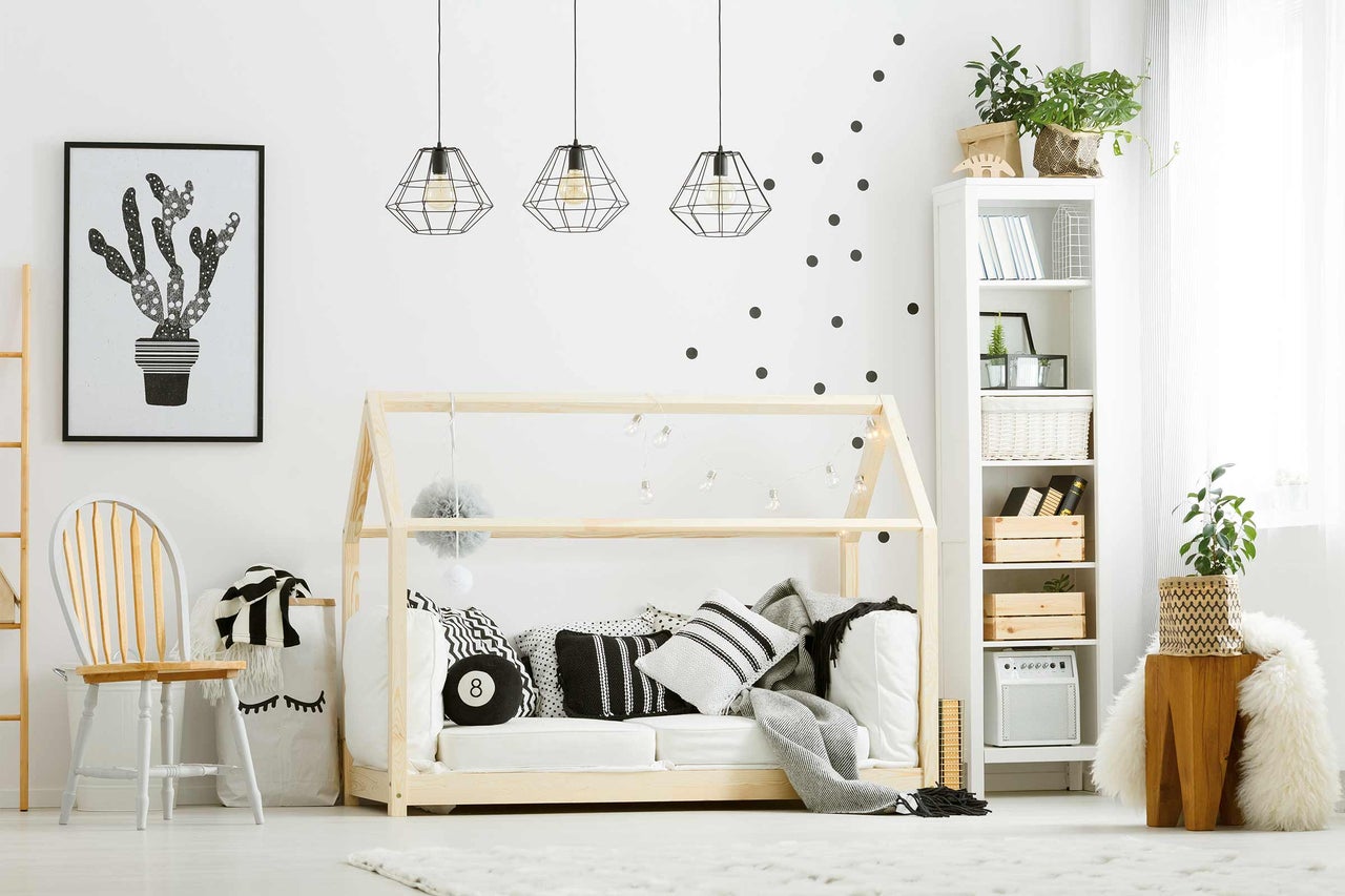 Helles Kinderzimmer mit Holzbettgestell, Kissen, Dekoration und Bücherregal