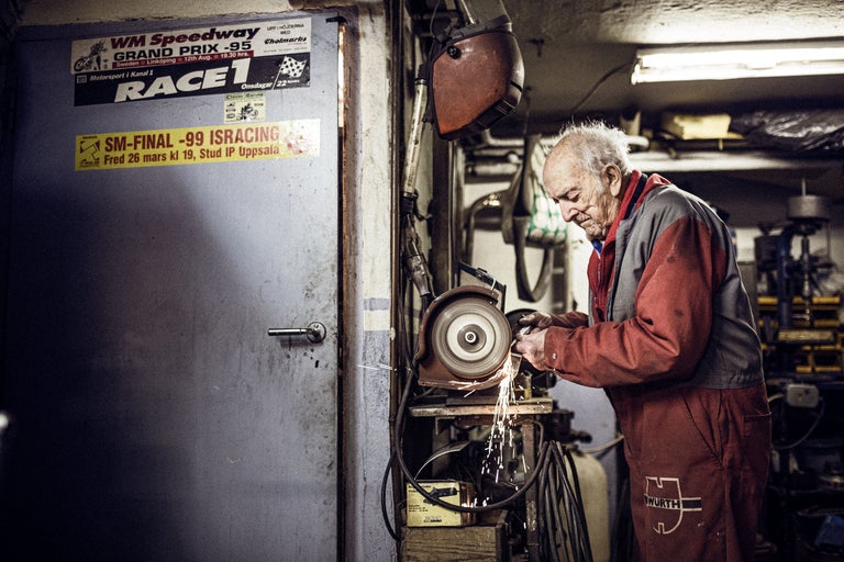 Ein Mann arbeitet mit einer Schleifmaschine in einer Werkstatt. Im Hintergrund befindet sich eine Tür mit Aufklebern und ein Schweißhelm. Ein Würth Logo ist auf seiner Arbeitskleidung zu sehen.