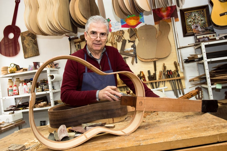 Gitarrenbauer bei der Arbeit an einer Gitarre in seiner Werkstatt.