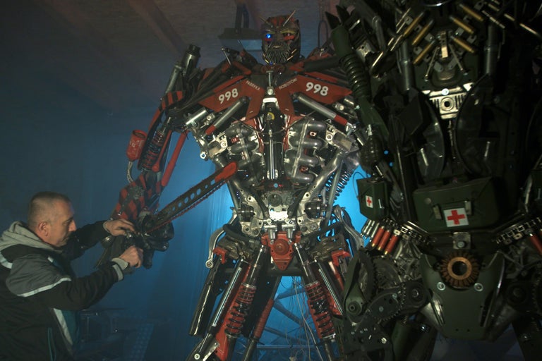 Zwei große Roboterfiguren aus Metall, darunter eine in Rot und Silber, die andere in dunkler Farbe