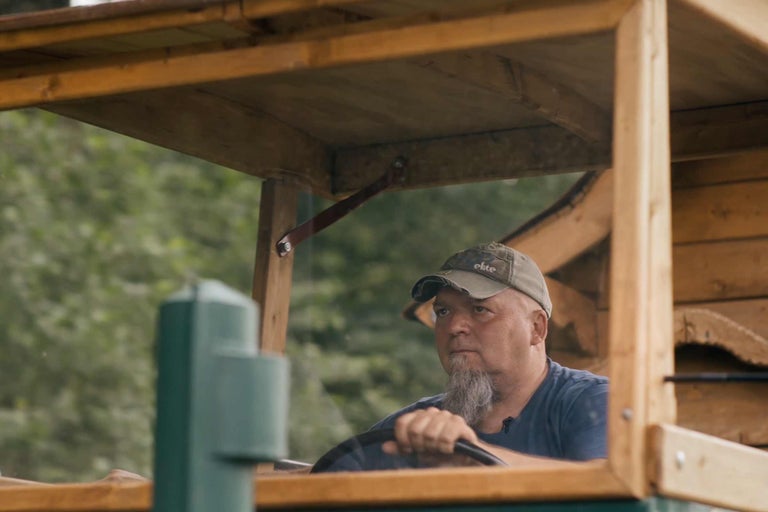 Mann steuert hölzernen Traktor