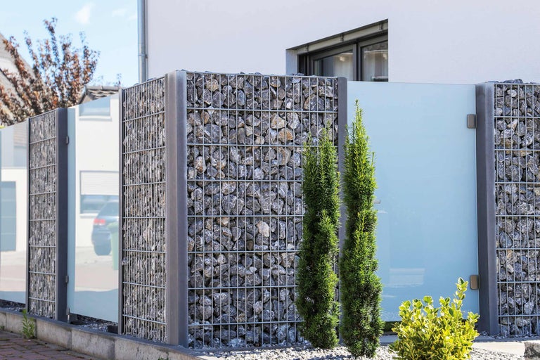 Gabionenzaun mit Steinfüllung und Glaselementen als Sichtschutz