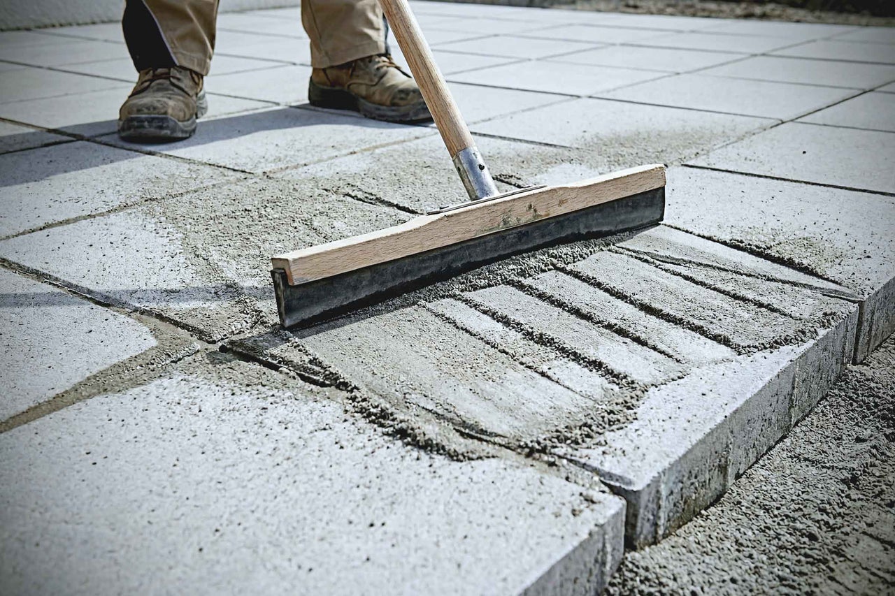 Einkehrmittel wird mit einem Gummischieber in das Pflaster gefegt