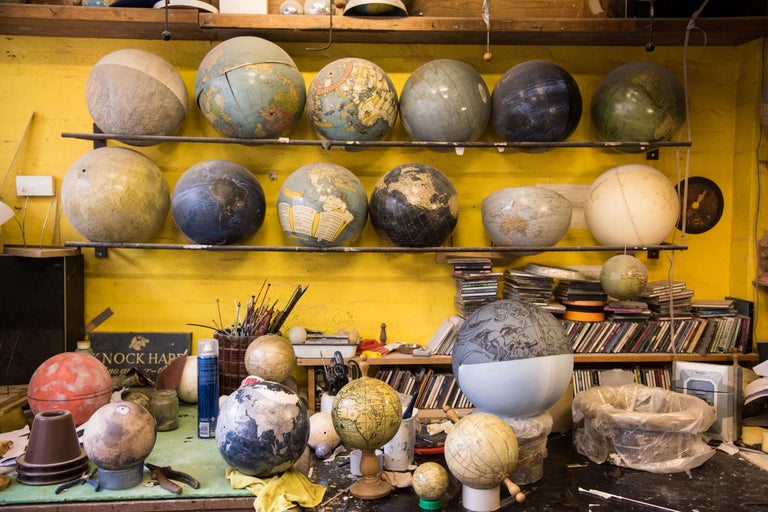 Ansicht eines Arbeitsbereichs mit Regalen und einem Tisch voller Globen