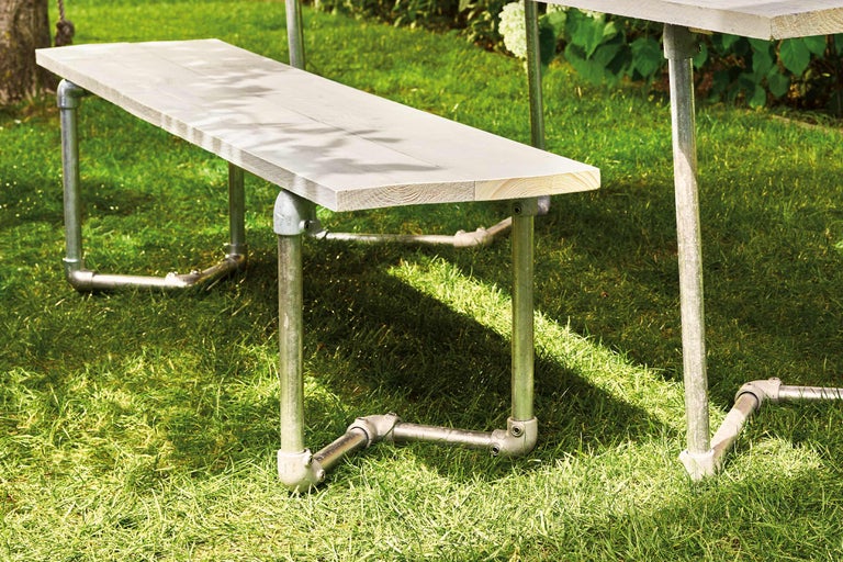 Gartenszene mit Holzbänken und Tisch mit Metallgestell auf Rasen