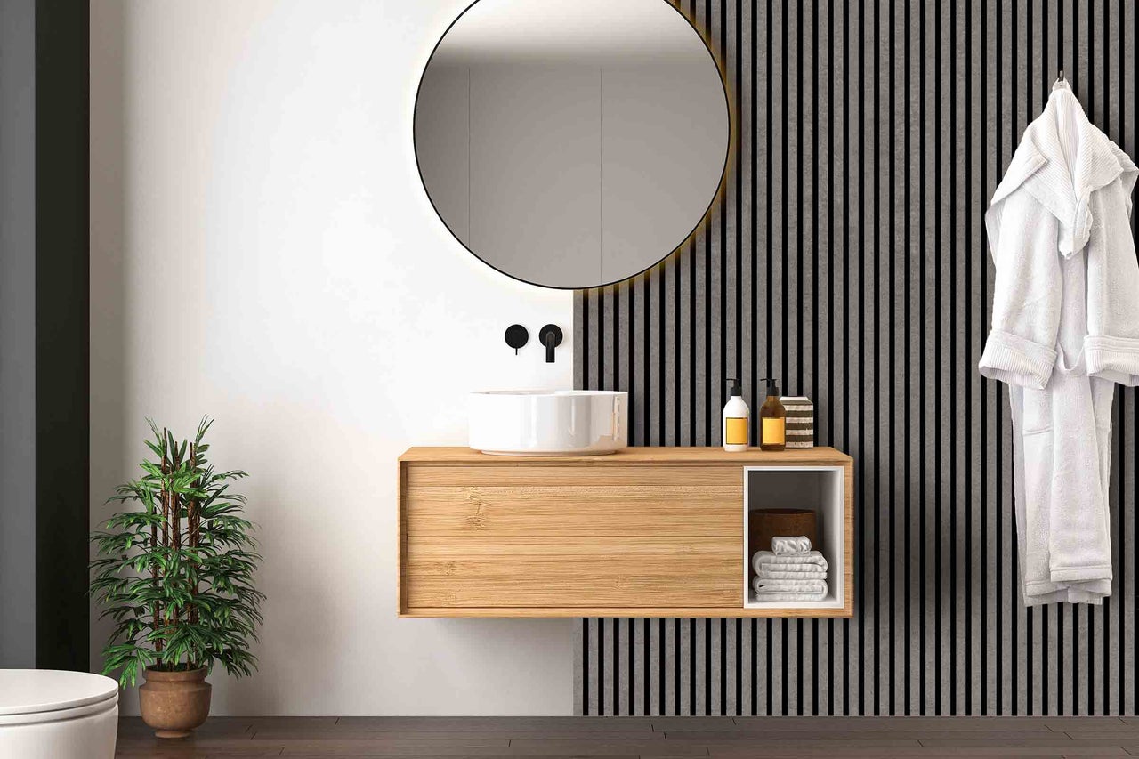 Modernes Badezimmer mit Waschtisch aus Holz, rundem Spiegel und Zimmerpflanze