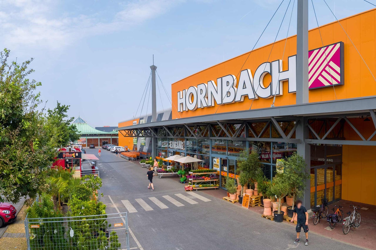  Außenansicht eines Hornbach Baumarktes mit Eingangsbereich, Pflanzen und Kunden 