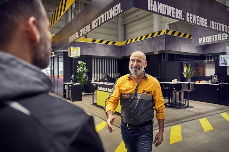 Ein Hornbach Mitarbeiter begrüßt einen Kunden im ProfiTreff Bereich des Marktes.