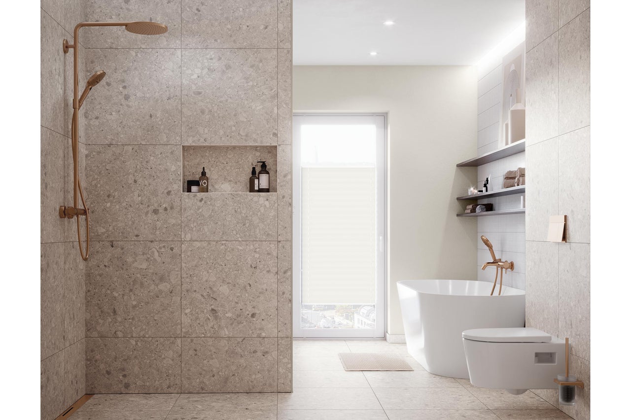 Modernes helles Badezimmer mit begehbarer Dusche in Steinoptik, freistehender Badewanne, Wandtoilette und Armaturen in Kupfer-Optik.