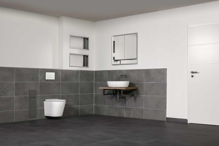 Badezimmer mit Wand-WC, Waschbecken auf Holzkonsole, Spiegelschrank und grauen Fliesen.