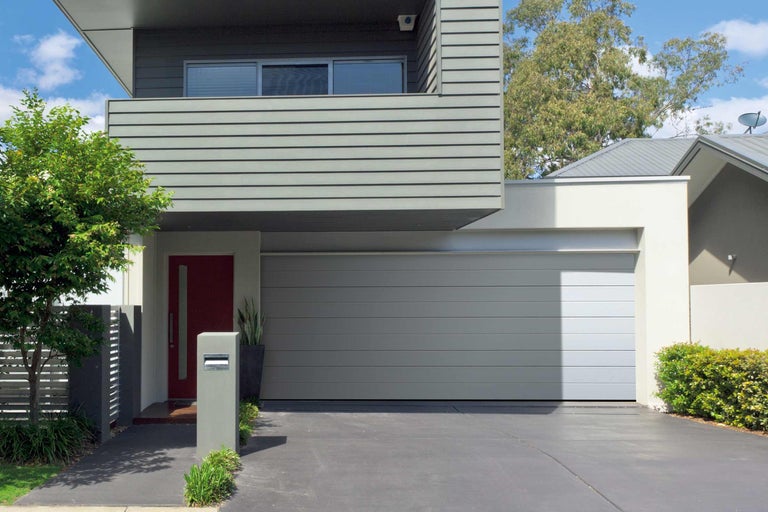 Modernes Haus mit grauer Garage und roter Haustür.