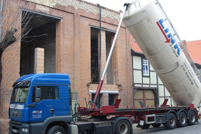 Blauer LKW mit Silo vor einem Gebäude