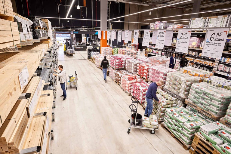 Innenansicht eines Hornbach Baumarktes mit Baumaterialien und Kunden beim Einkaufen.