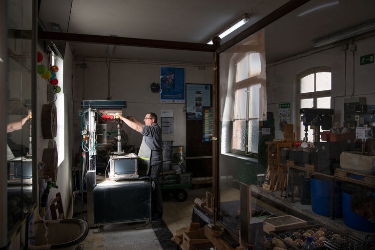 Werkstatt mit Werkzeugmaschinen und einer Person, die an einer Maschine arbeitet.