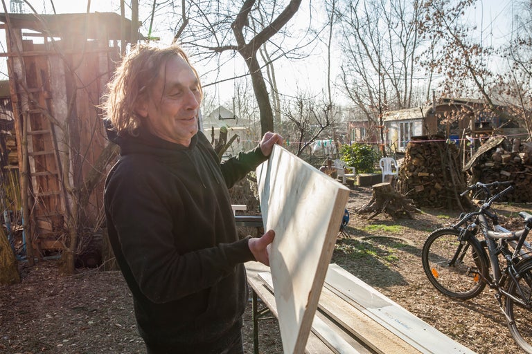 Mann hält Holzbrett im Garten