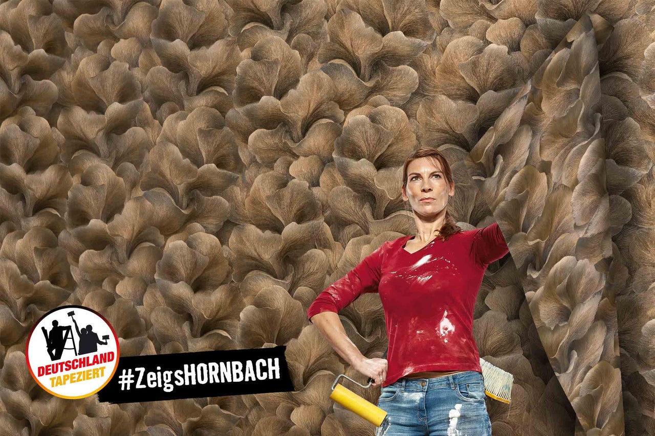 Frau tapeziert Wand mit Vliestapete mit Blattmuster