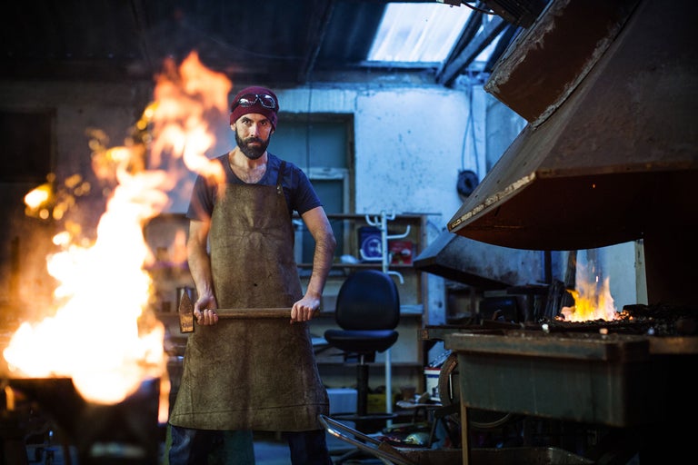 Schmied mit Hammer, Amboss und Feuer in Werkstatt