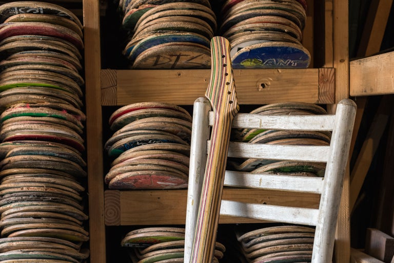 Gestapelte Skateboards in einem Holzregal mit einem Gitarrenhals