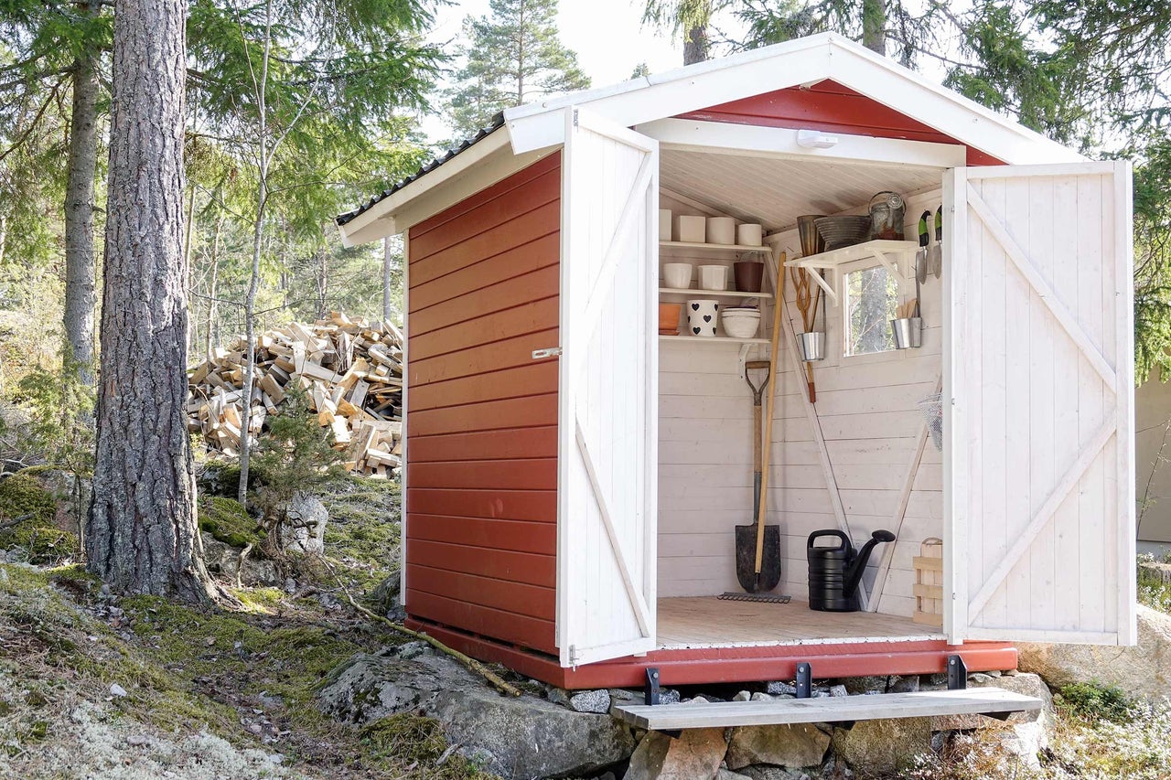 Gartenhaus mit geöffneten Türen, Gartengeräten und Pflanzenutensilien