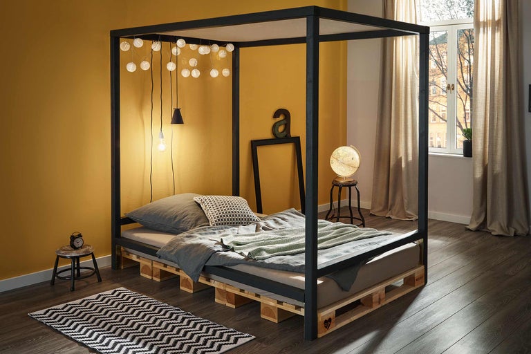 Schlafzimmer mit Himmelbett aus Holzpaletten und Dekoration