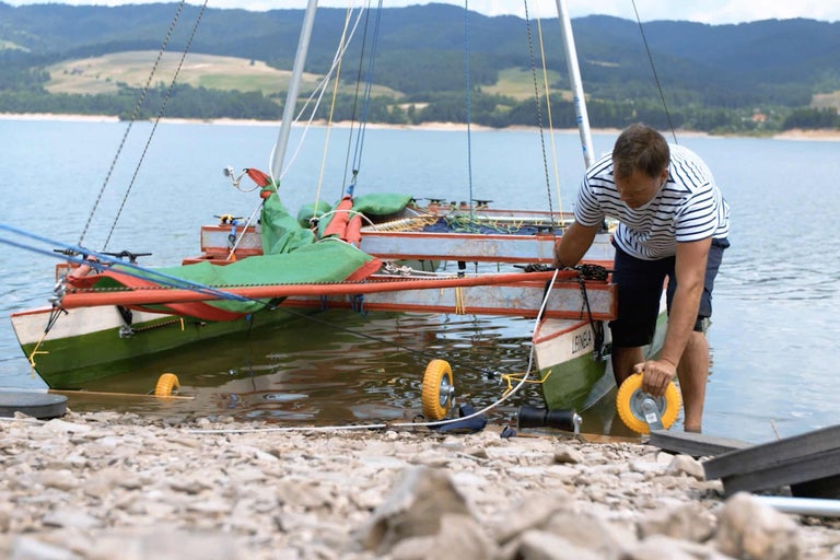 Mann bereitet Segelboot am See vor