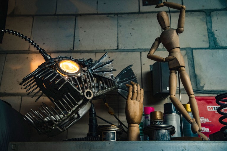 Dekorative Szene mit einer Fischlampe aus Metall, einer hölzernen Gliederpuppe und einer hölzernen Handattrappe