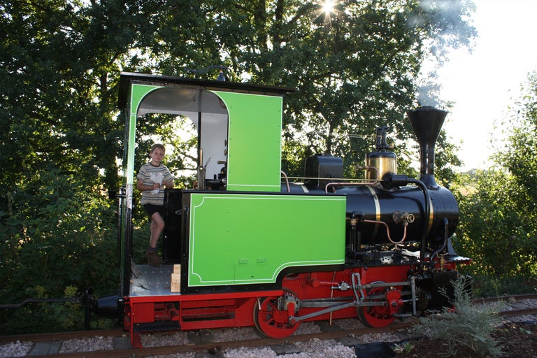 Dampflokomotive auf Schienen mit einer Person in der Kabine