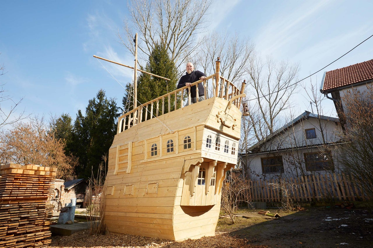 Großes hölzernes Spielschiff mit Mann an Deck im Außenbereich.