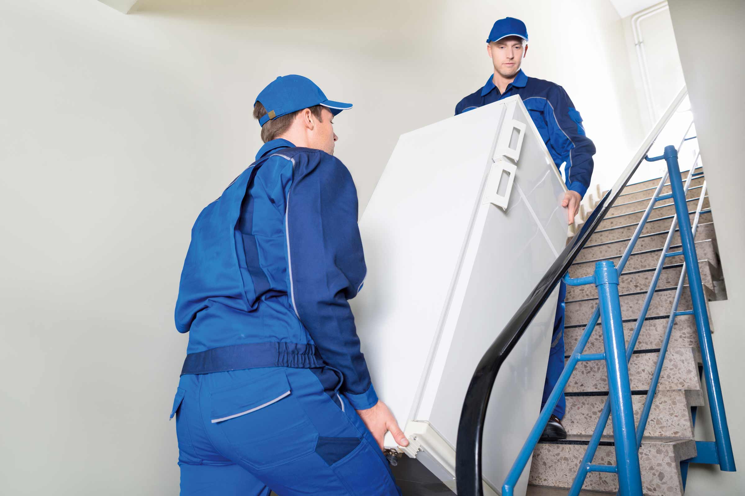 Zwei Arbeiter tragen einen Kühlschrank die Treppe hoch