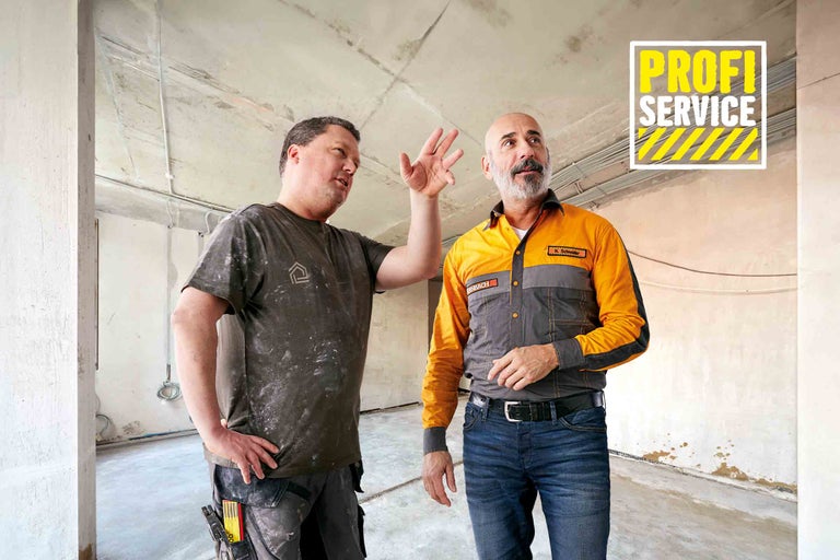 Zwei Handwerker bei der Arbeit in einem unfertigen Raum. Hornbach Profi-Service.