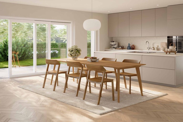 Heller Essbereich mit Esstisch, Stühlen, Teppich und Küchenzeile.