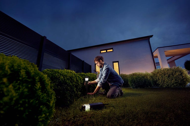 Mann installiert Gartenleuchten im Garten.