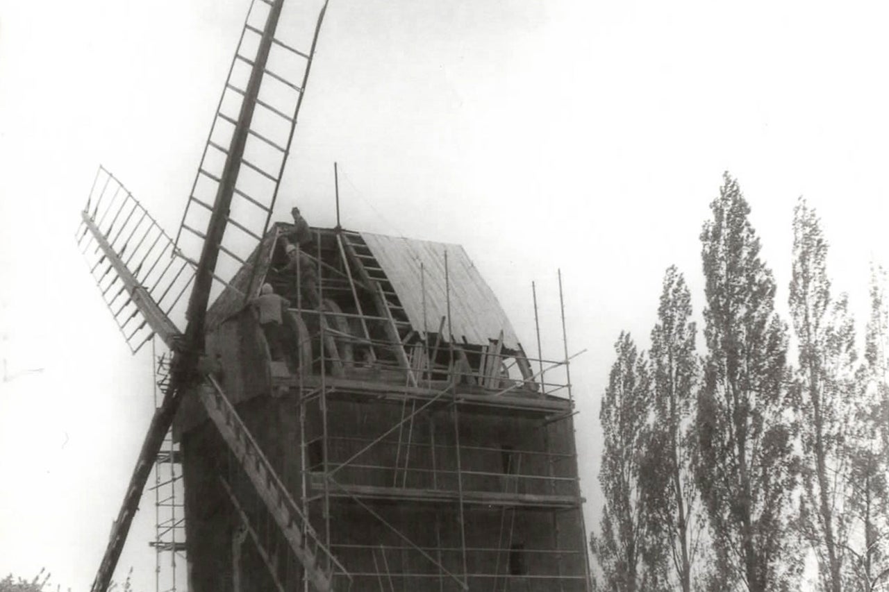 Windmühle unter Reparatur mit Baugerüst und Handwerkern
