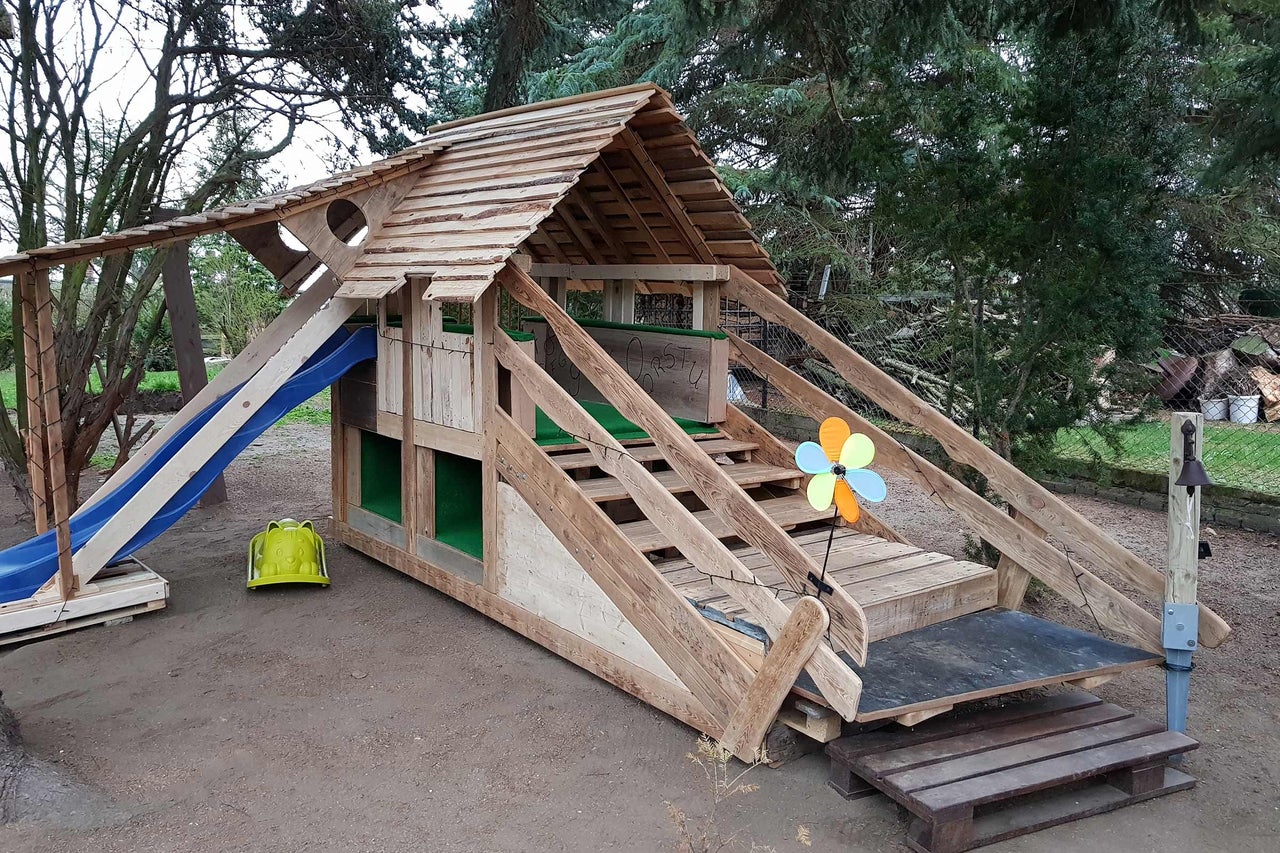 Holzspielhaus mit Rutsche und Treppe im Garten