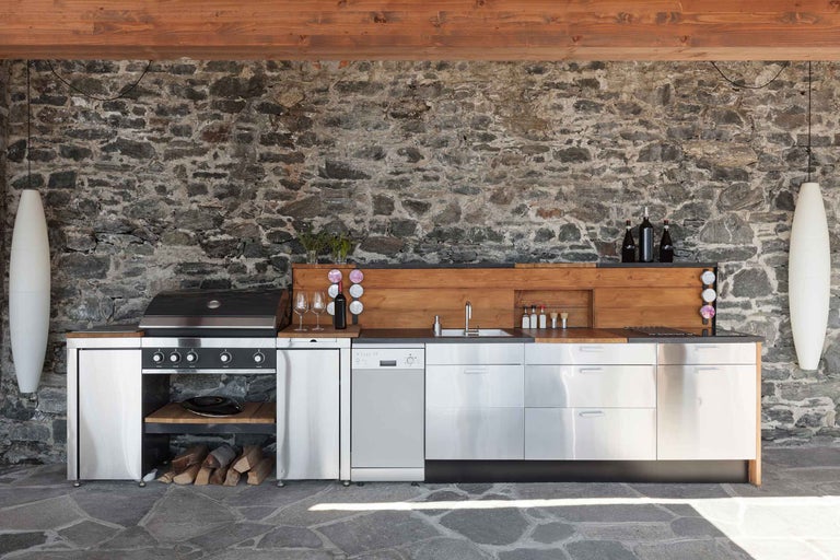 Außenküche mit Grill, Spüle, Arbeitsflächen und Steinwand