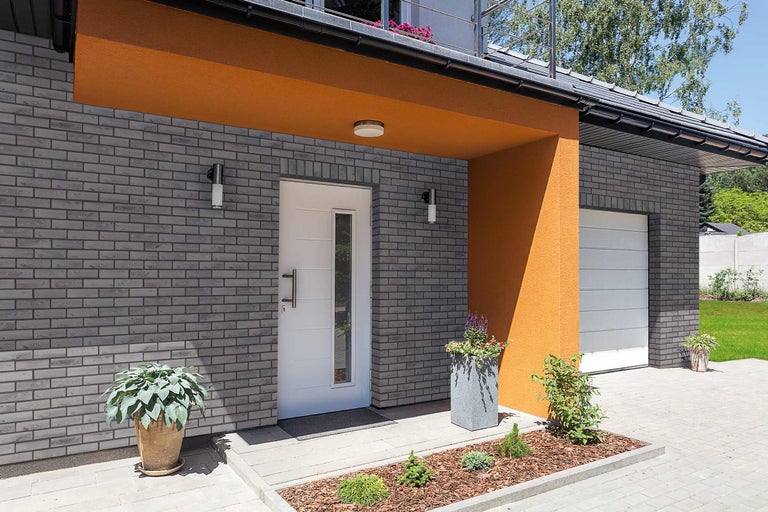 Außenansicht eines Hauses mit Klinkerfassade, Haustür und Garage