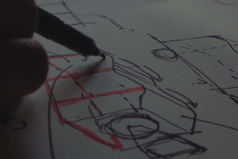Hand beim Zeichnen einer technischen Skizze mit einem Stift auf Papier