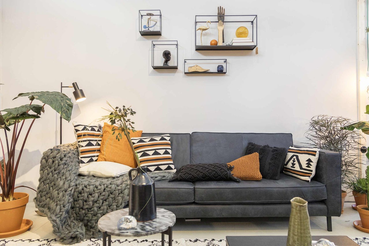 Wohnzimmer mit Sofa, Kissen und Wandregalen als Raumdekor