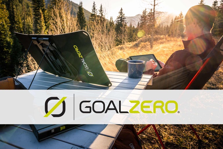Person benutzt Tablet mit Goal Zero Solarmodul und Campingtisch im Freien. Goal Zero Logo